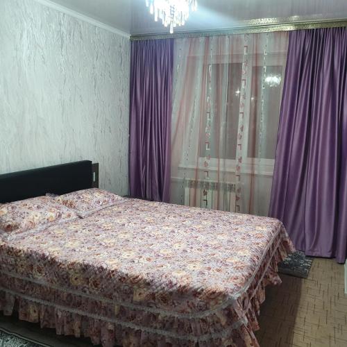 una camera da letto con un letto con tende viola e un lampadario a braccio di 2х ком квартира в Центре города ad Aqtöbe