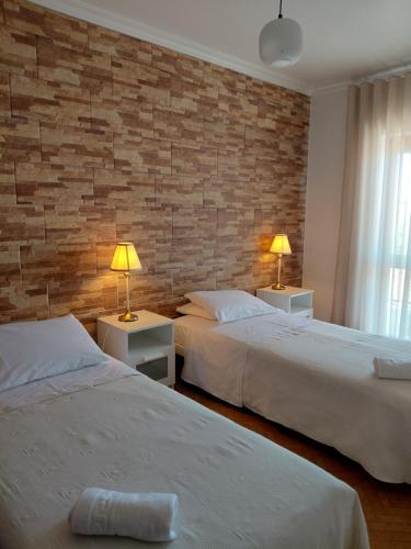 two beds in a room with a brick wall at Vila Morena in Grândola