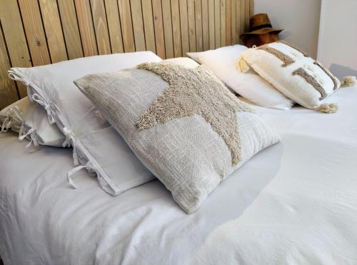 a bed with white pillows and a hat on it at L'Oustalou - Suite de 19m² aux portes de l'Aubrac in Aumont-Aubrac