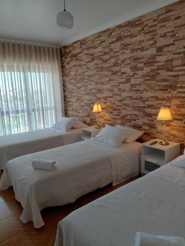 a bedroom with two beds and a brick wall at Vila Morena in Grândola