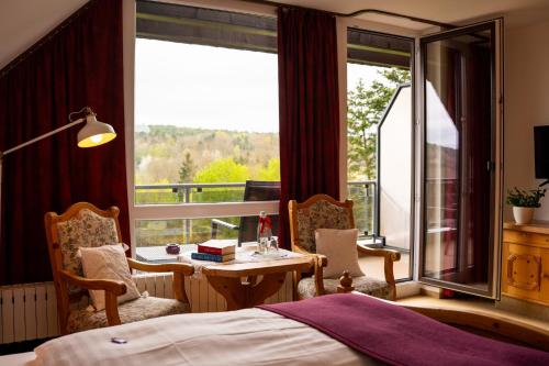 a bedroom with a bed and a table and a window at Landhotel Hubertus in Unterelsbach