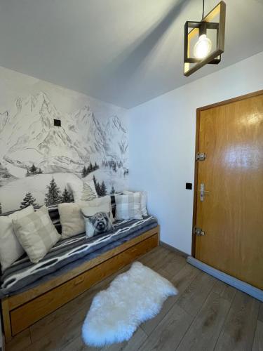 une chambre avec un canapé avec une fresque de montagne sur le mur dans l'établissement Studio Carroz d'Arâches 4 pers, à Arâches-la-Frasse