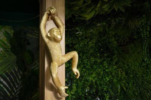 un lézard en métal doré accroché à un mur dans l'établissement Cap Jungle Evasion: Cinema Netflix King size, à Limoux