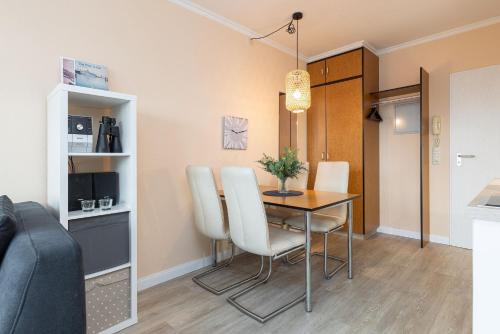 a dining room with a table and white chairs at Haus Panorama Laboe Nr 21 in Laboe