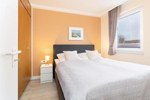 a bedroom with a white bed and a window at Haus Panorama Laboe Nr 21 in Laboe