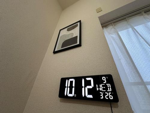 a clock on a wall next to a window at Stella 202 エアコン付 無料WiFi Netflix in Sapporo