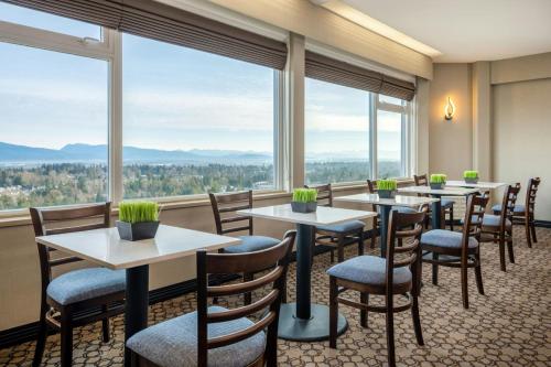 a restaurant with tables and chairs and large windows at Sheraton Vancouver Guildford Hotel in Surrey