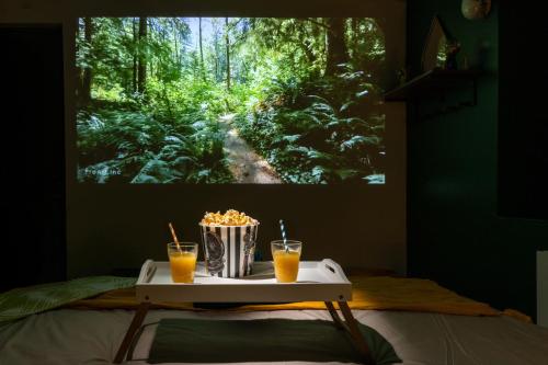 a table with two drinks on a bed with a picture of a forest at Cap Jungle Evasion: Cinema Netflix King size in Limoux