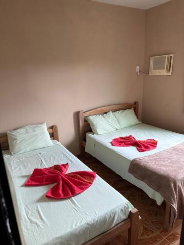 Duas camas com arcos vermelhos num quarto em Pousada Rodrigues em Itaobim