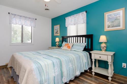 a bedroom with blue walls and a bed with two tables at Sunny Vacations Cottage by Bryant Real Estate in Kure Beach