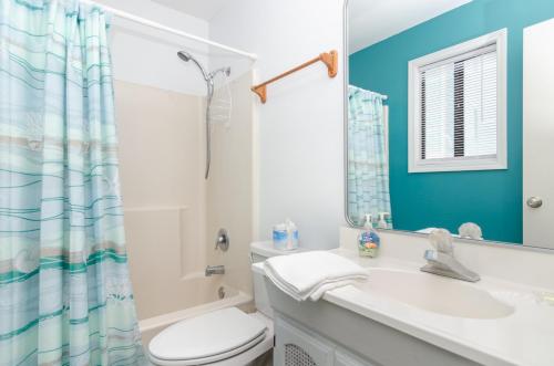 a bathroom with a toilet and a sink and a mirror at Sunny Vacations Cottage by Bryant Real Estate in Kure Beach