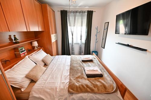 une chambre avec un grand lit avec une télévision à écran plat dans l'établissement Apartment Olivia, à Zadar