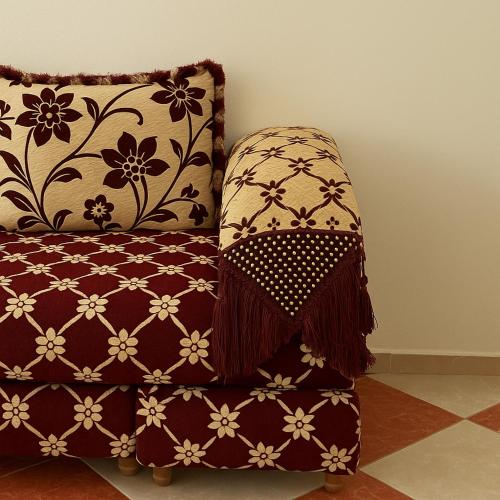 a red chair with a blanket and a pillow at Residence Kawtar Meknès Marjane 2 in Meknès