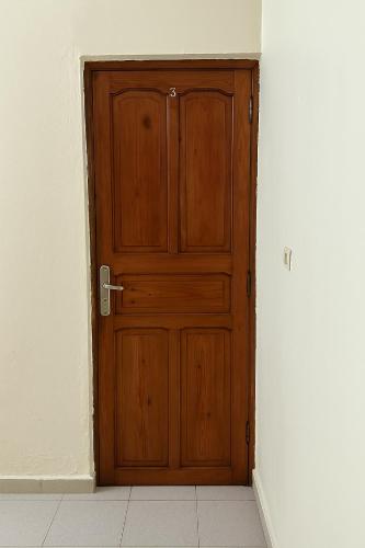a wooden door in a room with a white wall at Residence Kawtar Meknès Marjane 2 in Meknès
