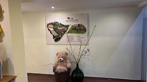 ein Teddybär sitzt neben einer Vase in der Unterkunft Ihr Ferien Hotel Brunnenhof in Suhlendorf