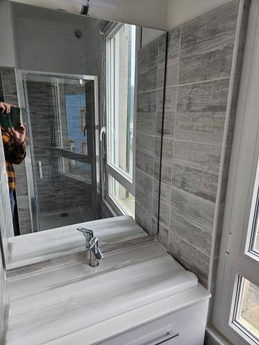 une salle de bain avec un lavabo et un miroir dans l'établissement appartement terrasses poulpatre, à Crozon