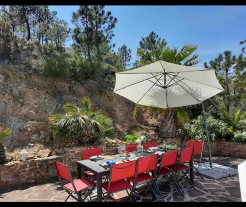 - une table avec des chaises rouges et un parasol dans l'établissement Villa Anthea, à La Celle-sous-Gouzon