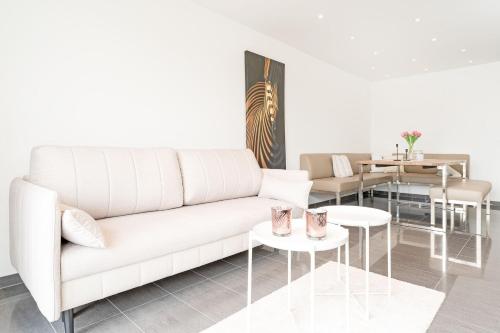 a living room with a white couch and tables at Strandvilla Augustusbad Meerverliebt in Scharbeutz
