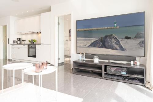a white kitchen with a large tv on a wall at Strandvilla Augustusbad Meerverliebt in Scharbeutz