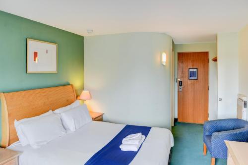 a hotel room with a bed and a chair at Belvilla Aberdeen Bridge of Don Exhibition Centre in Aberdeen