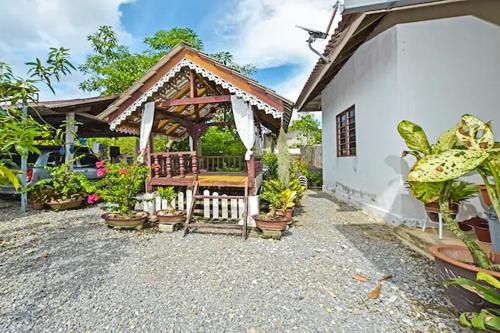 a house with a gazebo with potted plants at Homestay Masha Padang Besar in Padang Besar
