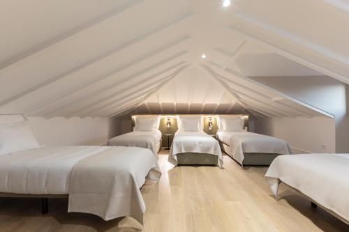 four beds in a room with a roof at Alojamento da Vila Golden in Valença