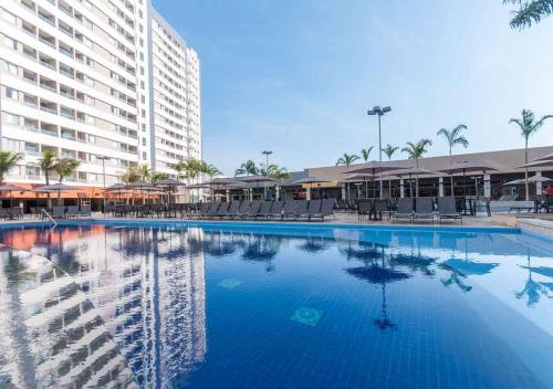 a large swimming pool with chairs and a large building at Ideal para famílias, hospede-se no Solar das Águas. in Olímpia