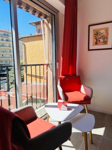 Il comprend un salon avec une chaise rouge et un balcon. dans l'établissement Riviera Sun, à Nice