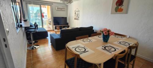 un salon avec une table avec un vase de fleurs dessus dans l'établissement Le fidgi - T3 6 personnes Parking privé Clim Terrasse proche plages, à Cagnes-sur-Mer