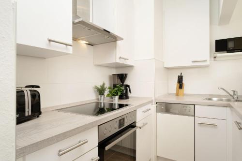 a white kitchen with white cabinets and a sink at Golfresidenz Ostseebude in Grömitz