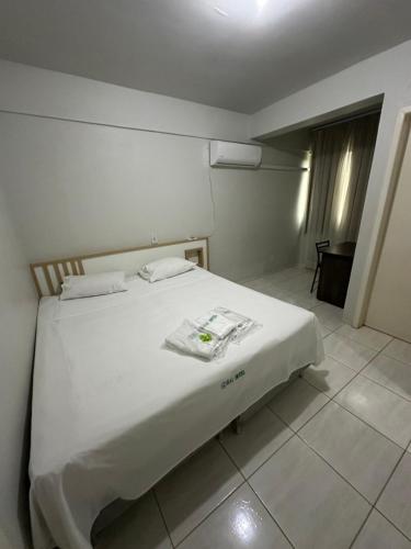 a bedroom with a white bed in a room at Rai Hotel - próximo a Prefeitura in Cascavel