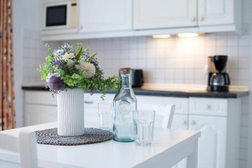 a white kitchen with a bottle and a vase with flowers at Seepferdchen Bargen in Hansaland