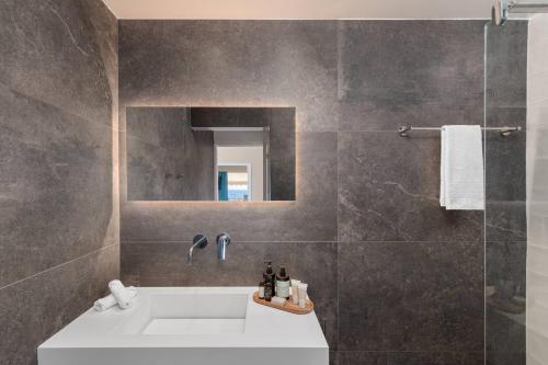 a bathroom with a sink and a shower with a mirror at 2bd Luxury Sea View Penthouse In Astir Beach in Athens