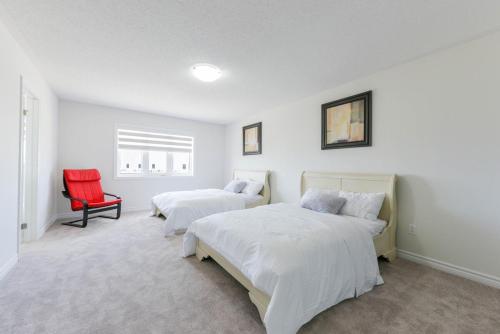 ソロルドにあるEntire 4BR Detached Home 15 Mins from the Falls, in Thorold, Perfect for 10 guestsのベッドルーム1室(ベッド2台、赤い椅子付)