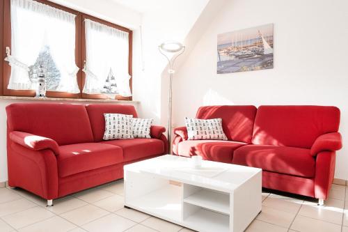 a living room with two red couches and a white table at Hasenkamp 18 Hummer in Grömitz