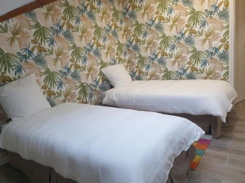 two beds in a room with a floral wallpaper at ODI RENT - Le 60 in Le Blanc-Mesnil