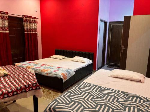 a bedroom with two beds and a red wall at IK Homestay in Varanasi