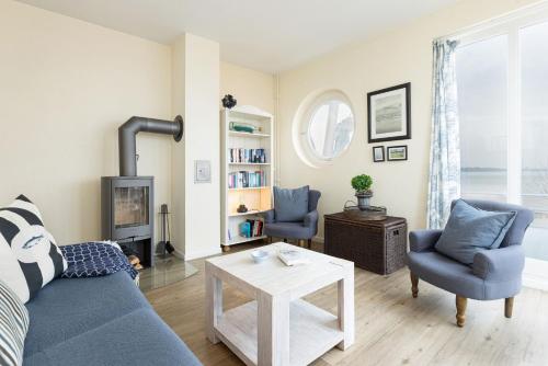 ein Wohnzimmer mit einem blauen Sofa und Stühlen und einem Kamin in der Unterkunft Haus Windjammer Strandliebe in Laboe