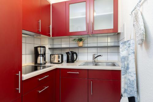 eine Küche mit roten Schränken und einer Spüle in der Unterkunft Haus Windjammer Strandliebe in Laboe