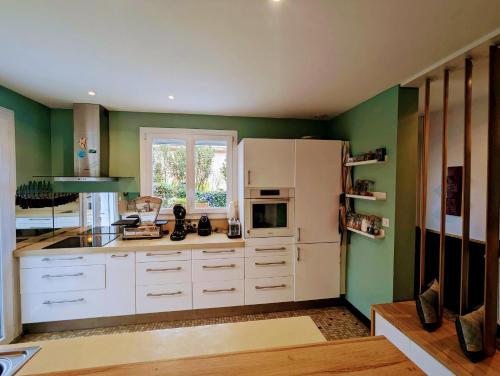une cuisine avec des armoires blanches et des murs verts dans l'établissement La Villa Montcalm, à Montpellier