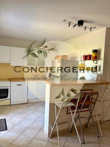 une cuisine avec des armoires blanches et une table et des chaises dans l'établissement Duplex La Favière Bormes-les-Mimosas, à Bormes-les-Mimosas