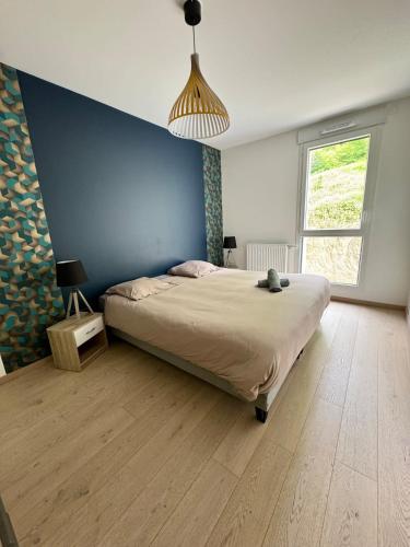 une chambre avec un grand lit et un mur bleu dans l'établissement Le Dolce lake beach parking, à Aix-les-Bains