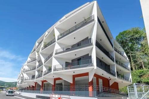 un grand bâtiment blanc avec des balcons sur une rue dans l'établissement Le Dolce lake beach parking, à Aix-les-Bains