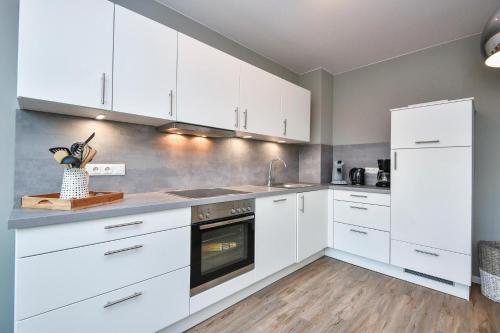 a kitchen with white cabinets and a sink and an oven at Ostseedomizil Beachloft in Kellenhusen