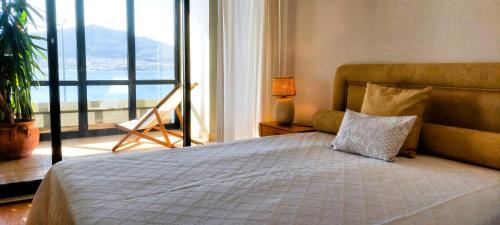 a bedroom with a large bed with a large window at Casa Foz do Rio in Caminha