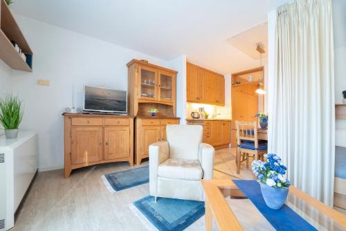a living room with a white chair and a television at Hamburger Straße 3- Wohnung 5 in Grömitz