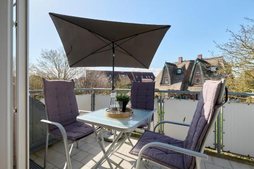 a table and chairs on a balcony with an umbrella at Wohnung 4 in Schönberger Strand