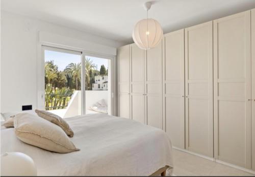 ein weißes Schlafzimmer mit einem Bett und einem großen Fenster in der Unterkunft SE8 - Stylish townhouse with rooftop terrace in Marbella