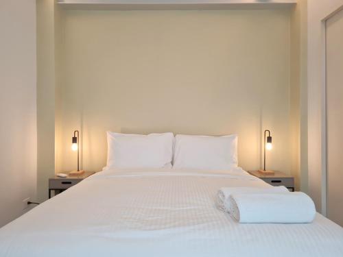 a white bed with two lamps and a towel on it at Lesplanade By Wynwood House in Panama City
