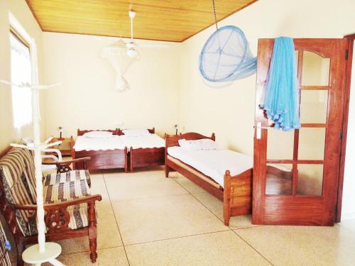 a room with two beds and a chair in a room at Mallika Guest House in Hikkaduwa